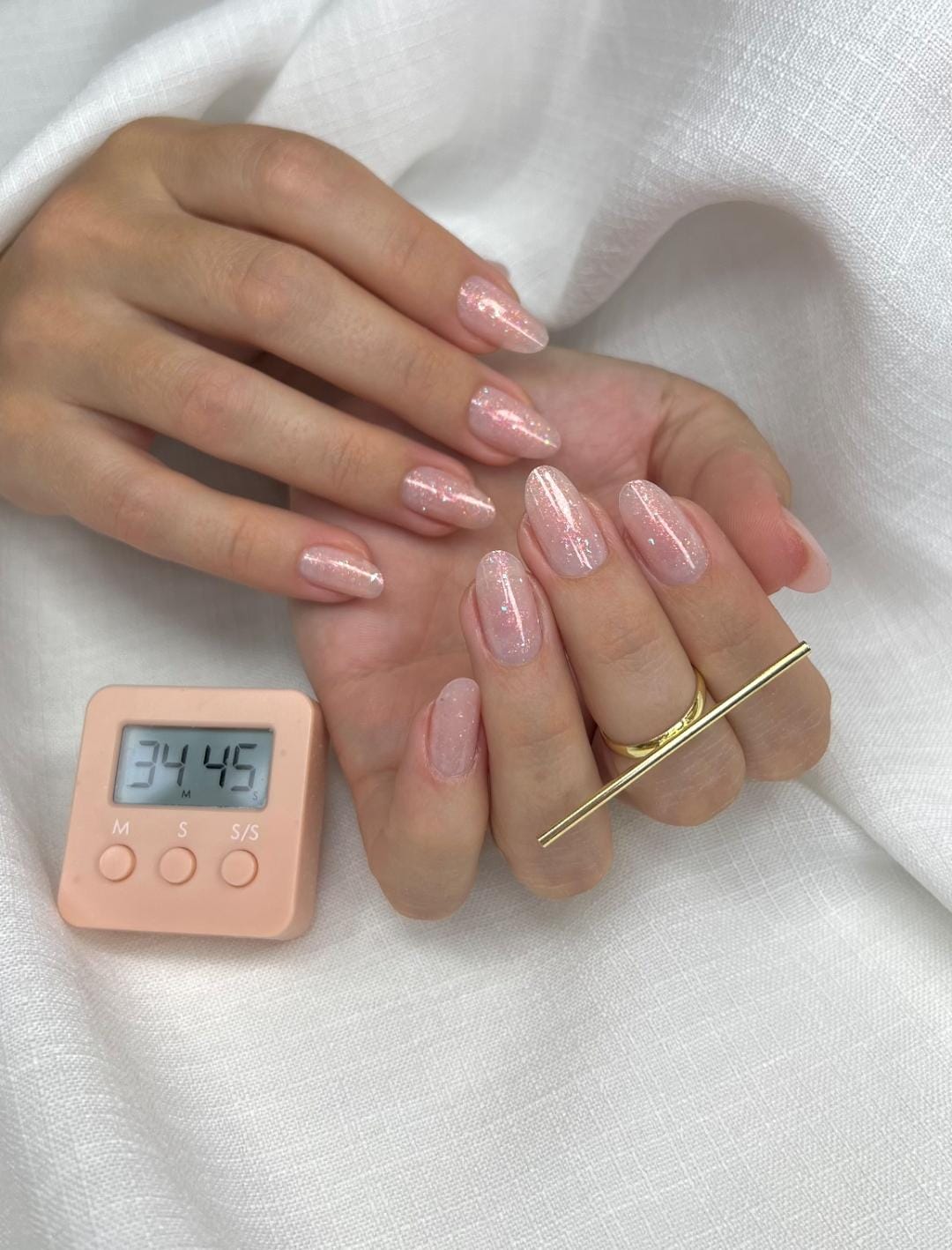 Unhas ovais nude com efeito glitter delicado