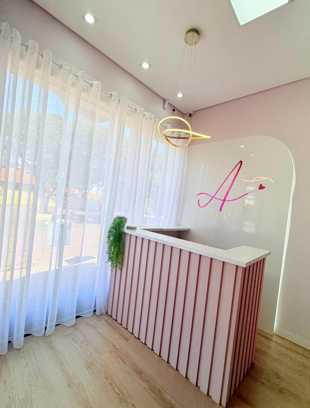 Recepção do Studio Ana Amélia com balcão rosé e logo iluminado