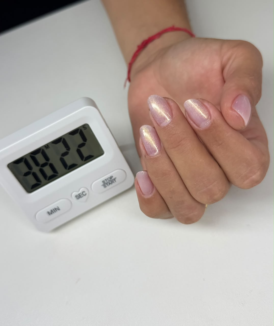 Unhas ovales rosa pálido com brilho dourado iridescente