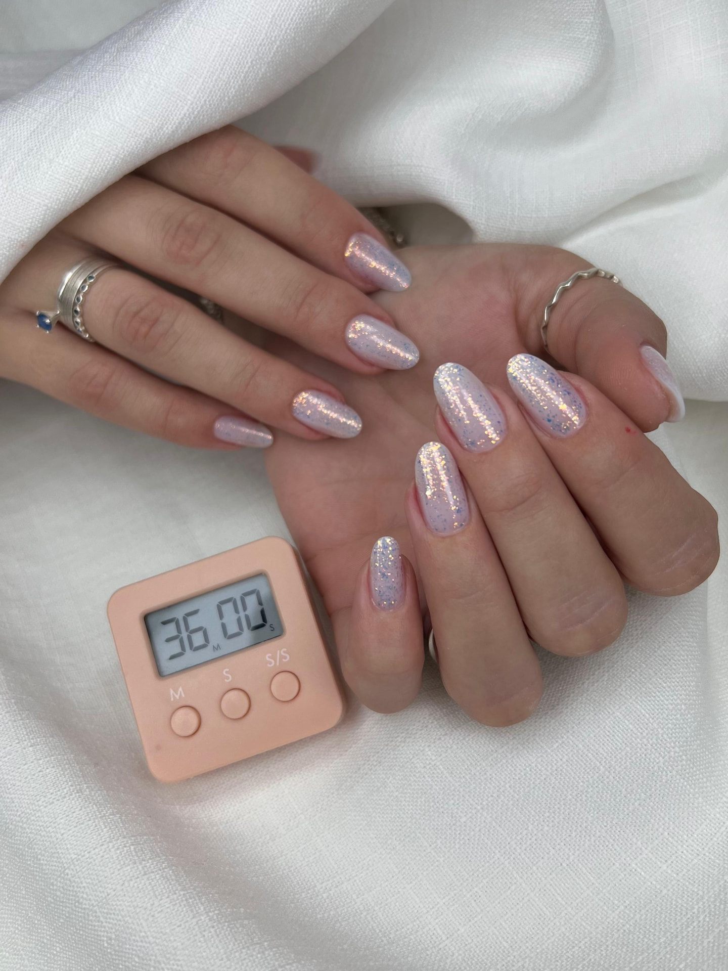 Unhas com glitter holográfico sobre base clara
