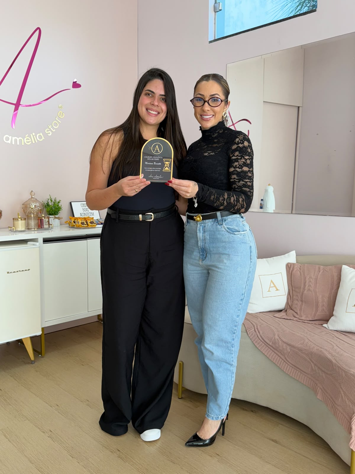 Aluna vestida de preto com Ana Amélia no estúdio, segurando placa de conclusão
